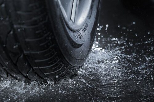 Close-up of a car tire splashing through water on a wet road