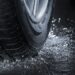 Close-up of a car tire splashing through water on a wet road