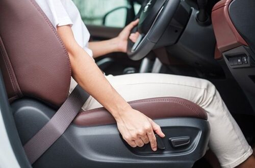 Driver reaching for a car seat adjustment lever while seated