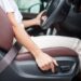 Driver reaching for a car seat adjustment lever while seated