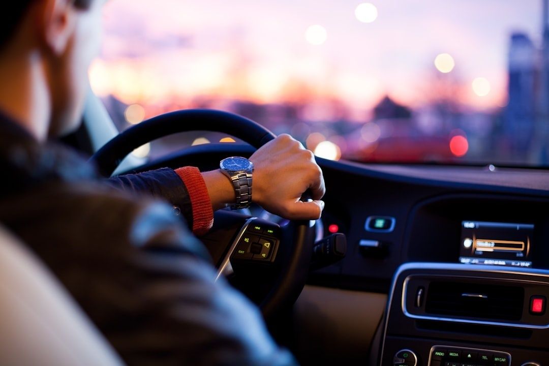 Driver gripping a car steering wheel during a blurred evening commute