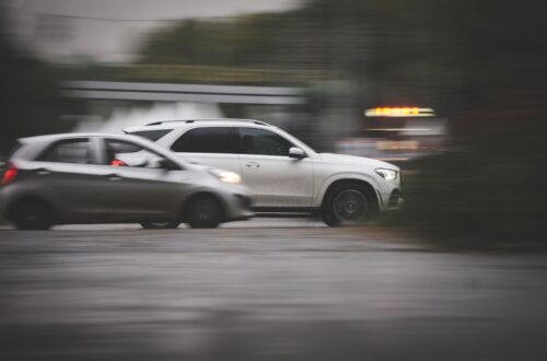 Two cars traveling side by side on a wet, blurred roadway