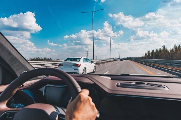Driver steering on a highway beside a white car during a merge