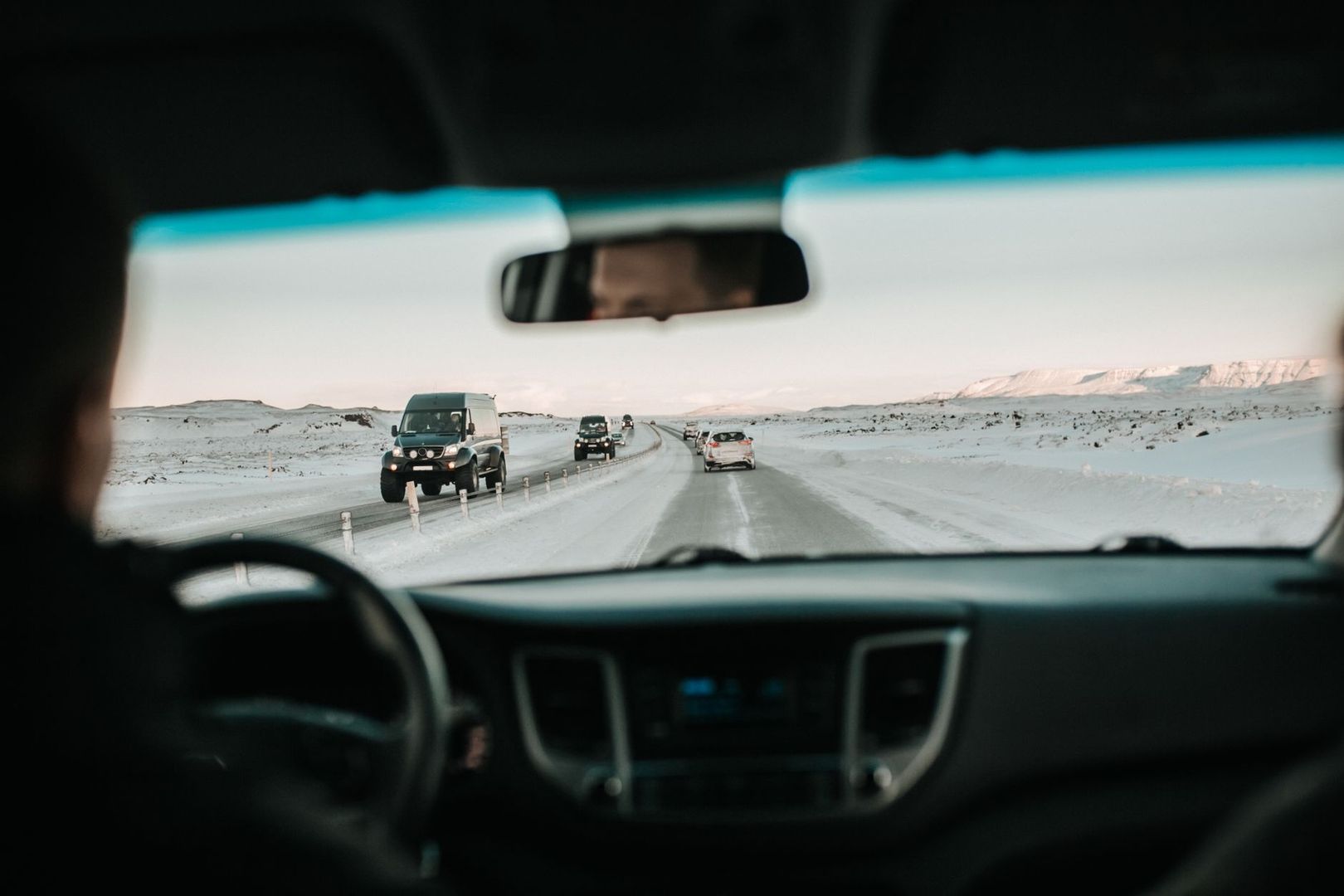 View through a car windshield of traffic on a snowy, icy road